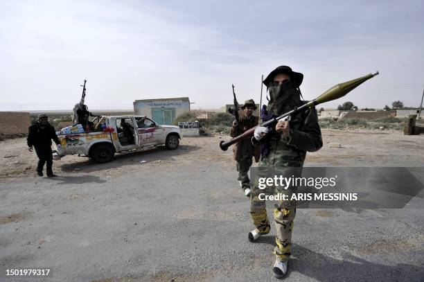 Armed Libyan rebels stand guard at a checkpoint outside the city of Brega on March 27, 2011 as rebels pushed westwards in hot pursuit of Moamer...