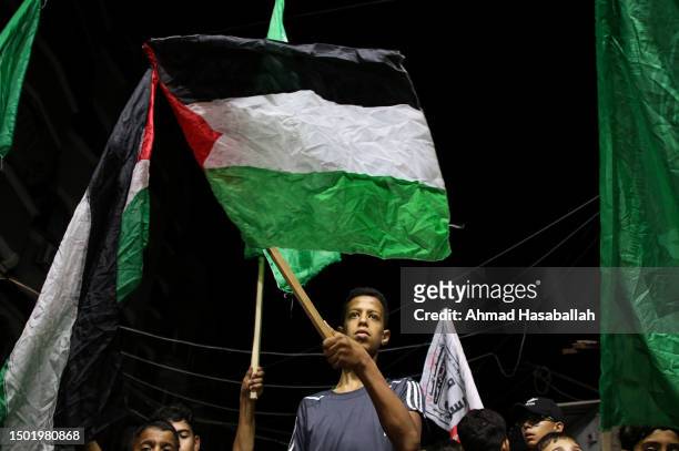 Palestinian raises the national flag during a solidarity demonstration to protest the storming of Jenin on July 4, 2023 in Gaza City, Gaza. 11...