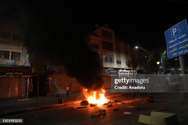 Palestinians burn car tires and block roads as they protest against Israel's ongoing airstrikes and raids on the second day in Jenin, in Hebron, West...
