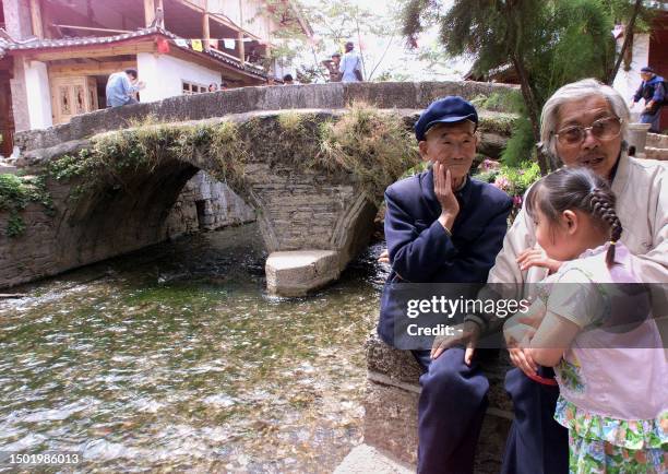 Two elderly men look after their grand-daughter as they sit beside a bridge in Lijiang's Old Town 03 May 1999, one of the World's cultural heritage...