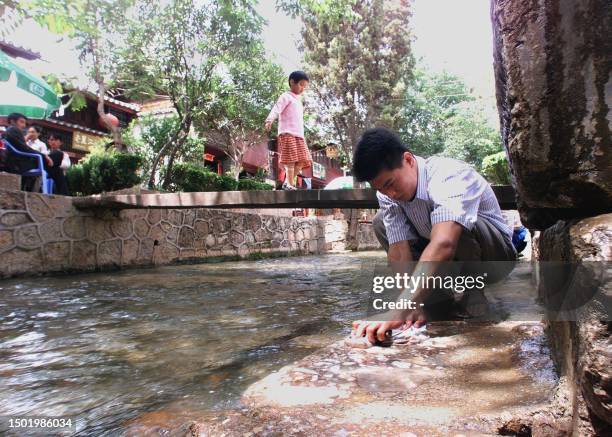 Man washes his clothes beside one of the many canals that run through Lijiang's Old Town 03 May 1999, one of the World's cultural heritage sites,...