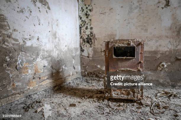 June 2023, Rhineland-Palatinate, Schuld: A rusty stove amid moldy walls and dried mud in a flood-ravaged abandoned house still hints at its former...