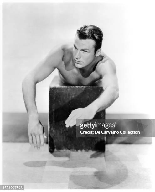 Publicity portrait of actor and swimmer Buster Crabbe on a platform teaching swimming movements United States.