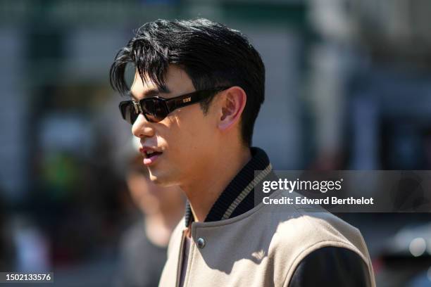 Eric Nam wears black sunglasses, a white t-shirt, a beige felt / wool with black shiny leather long sleeves teddy jacket, outside Sacai, during the...