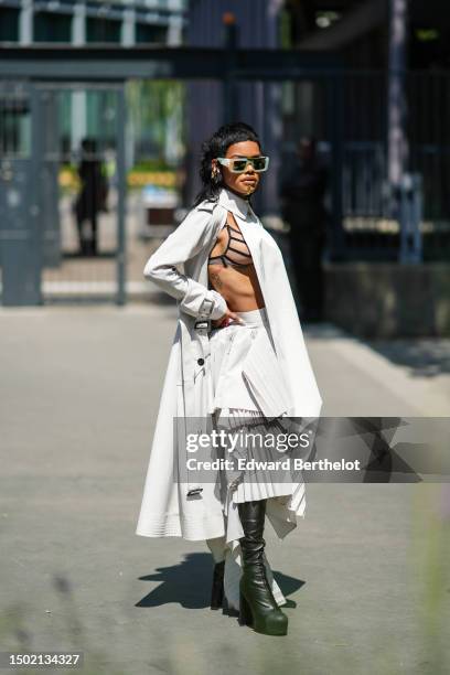 Teyana Taylor wears beige and green tie and dye print pattern sunglasses from Off-White, gold jewels, gold large earrings, a pale gray shirt neck /...