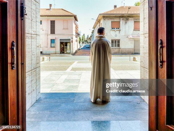 il parroco attende i fedeli per la messa sul sagrato della chiesa - cattolicesimo foto e immagini stock
