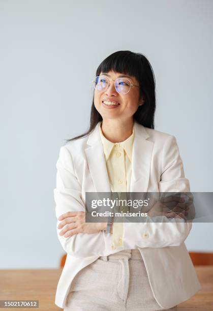 portrait d’une femme d’affaires souriante debout dans le bureau - regarder ailleurs photos et images de collection