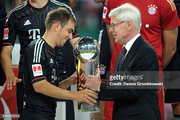 Reinhard Rauball, president of the German Football League DFL, hands over the trophy to Philipp Lahm of Bayern after the Bundesliga Supercup 2012...