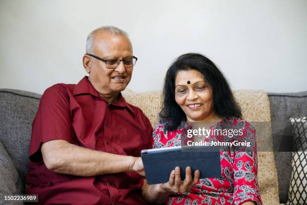 senior indian couple using digital tablet - couple candid stock pictures, royalty-free photos & images