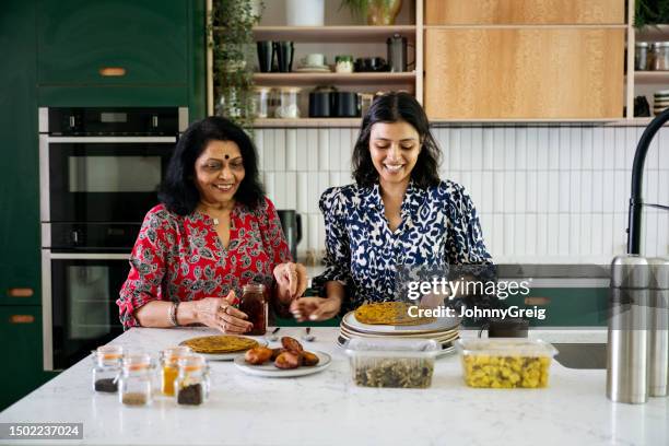 cheerful indian women preparing food in kitchen - bindi stock pictures, royalty-free photos & images