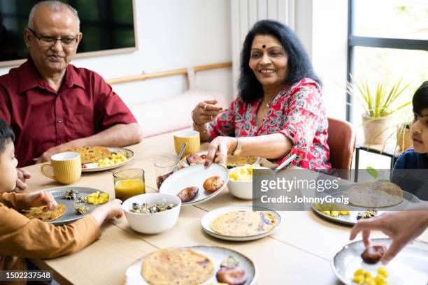 grandparents enjoying meal at home with grandchildren - vada stock pictures, royalty-free photos & images