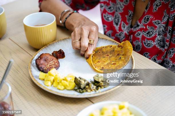 senior indian woman eating vegetarian food at midday meal - vada stock pictures, royalty-free photos & images