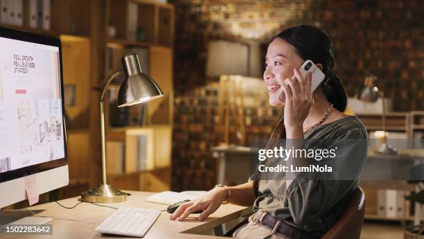 happy woman in office, phone call at computer and overtime at design agency, discussion and smile on deadline. late work, project manager or designer on mobile conversation, online planning at night. - employment agency stock pictures, royalty-free photos & images