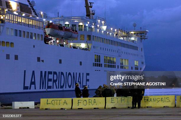 Des gendarmes mobiles maintiennent à l'écart, le 01 octobre 2005 à l'aube dans le port d'Ajaccio, une quinzaine de marins STC de la SNCM, après avoir...