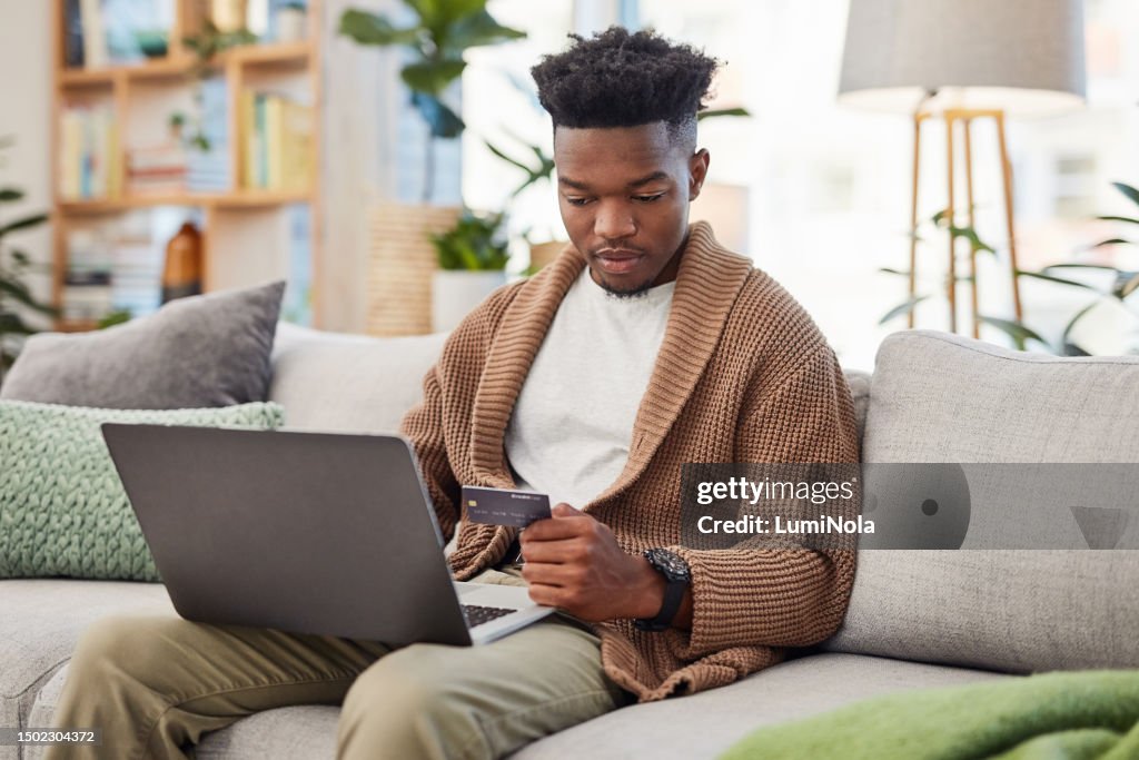 Online shopping, laptop and credit card, black man on sofa in living room and relax while internet banking in home. Technology, ecommerce payment and girl on couch browsing retail website for sale.