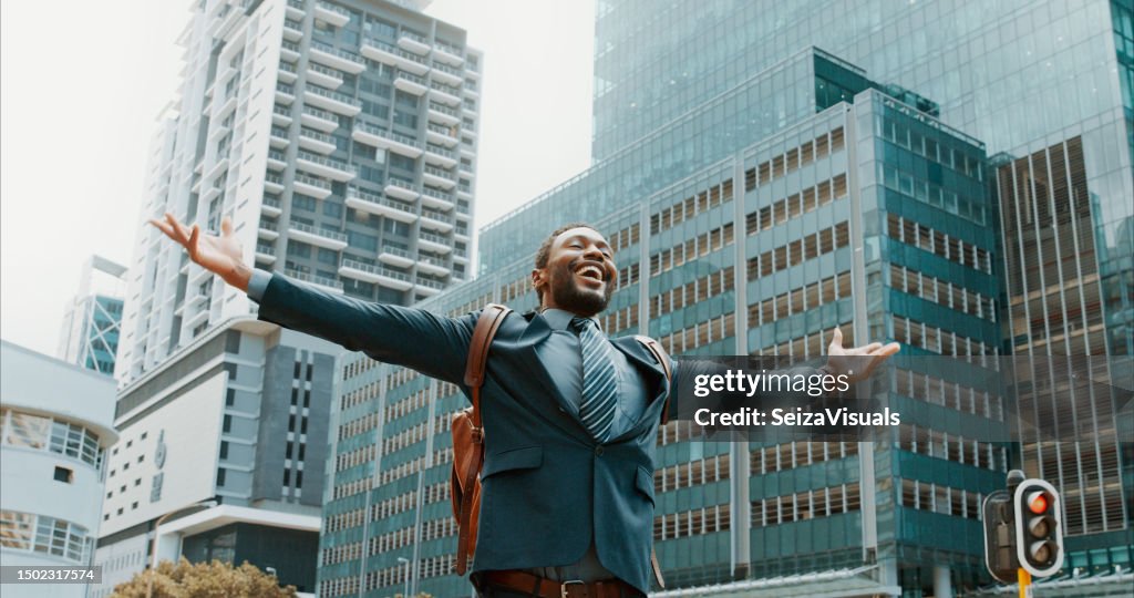 Open arms, celebration and business man in a city happy, excited and winner on urban background. Success, good news and African male winner cheerful for victory, accomplishment or job opportunity