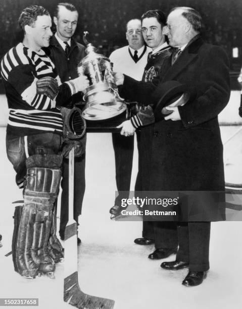 Frank Calder, president of the National Hockey League, presents the Vezina Trophy to Chicago Black Hawks' goalie Charles Gardiner , Chicago,...