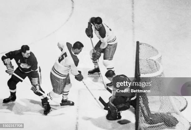 The Detroit Red Wings' Metro Prystai slashes the puck by the right side of the Montreal Canadiens' goalie Gerry McNeil and Bud MacPherson in a...