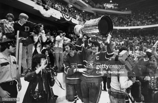 The Montreal Canadiens' captain Serge Savard lifts up the Stanley Cup trophy as he walks around the Boston Garden arena with teammate Larry Robinson...