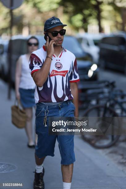 Fashion Week guest is seen wearing Ralphs cap, black shades, football tricot, denim blue capri pants, white socks and black loafer outside White...