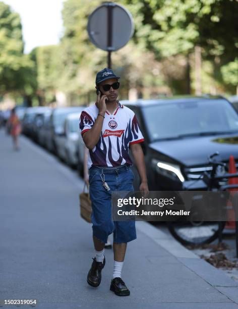 Fashion Week guest is seen wearing Ralphs cap, black shades, football tricot, denim blue capri pants, white socks and black loafer outside White...