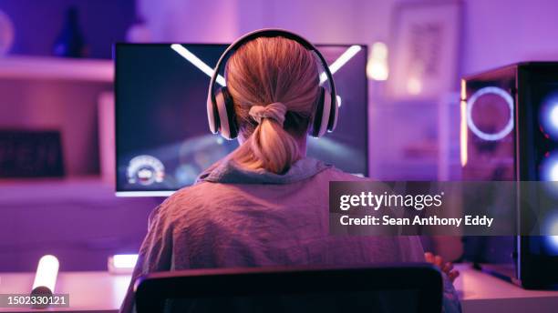 neon, gaming and back of woman with pc for live streaming esports, video games or virtual competition. desk, computer and female gamer with headphones for playing cyber, rpg and online game on screen - videospel stockfoto's en -beelden