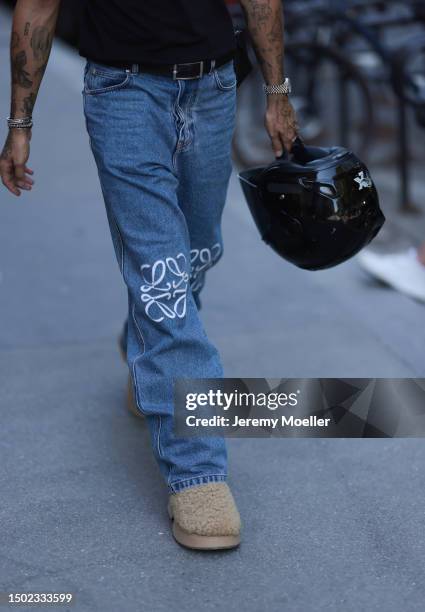 Fashion Week guest is seen wearing a Balenciaga black cap, Loewe black shirt, Loewe logo blue jeans and fluffy teddy shoes outside White...