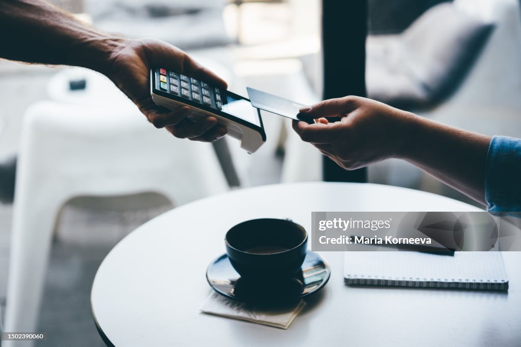 Woman pays with a card in a cafe.