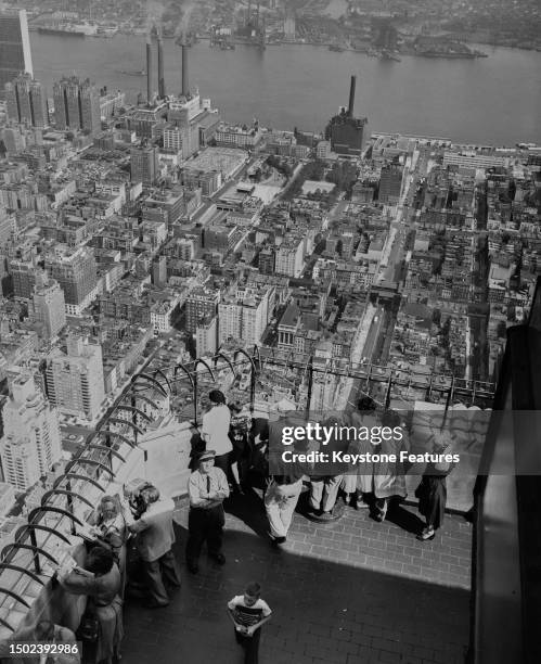 Crowd of people on the Observatory of the Empire State Building with the city and the East River below them in the background, New York, July 1953.