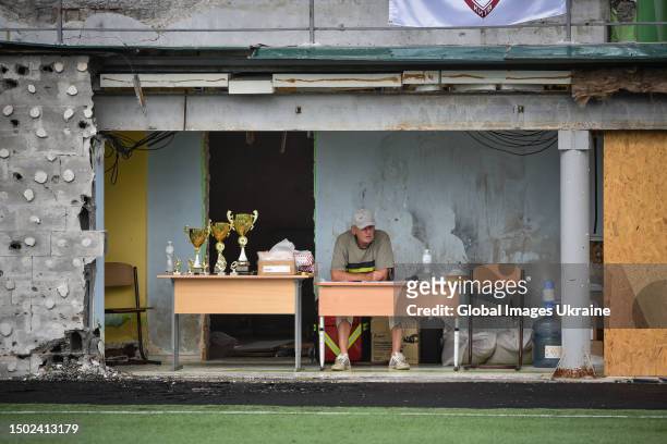 Man sits at the table next to the trophies and medals for the winners during the "Irpin Cup" tournament on June 24, 2023 in Irpin, Ukraine. The...