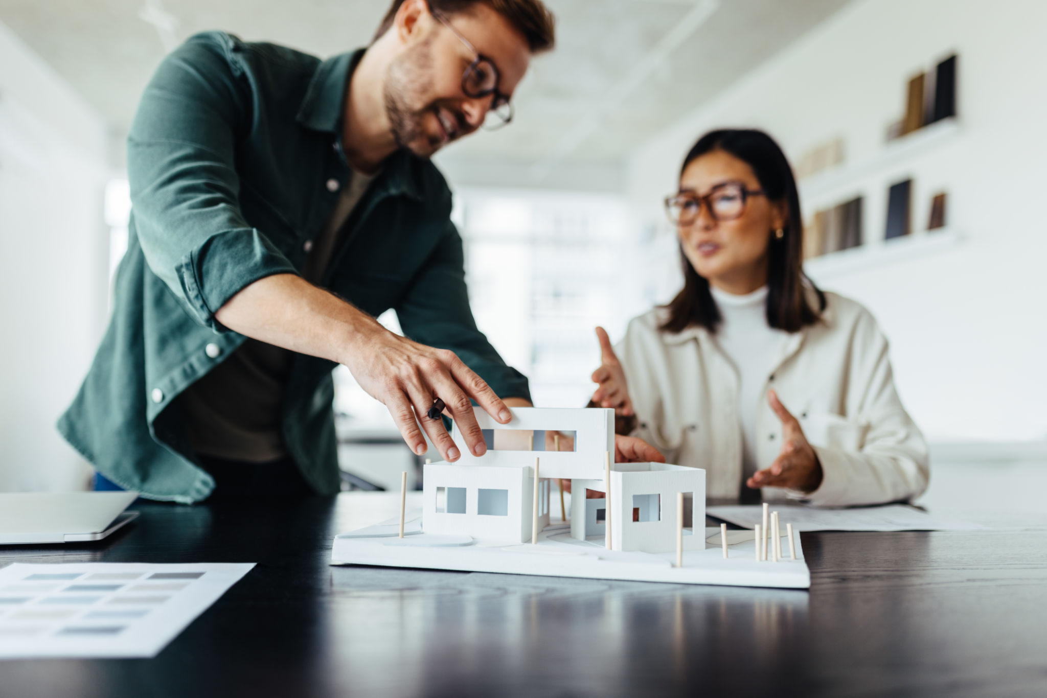 Architects working on a house model in an office Architects working on a house model in an office