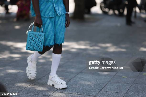 Fashion Week guest is seen wearing black balenciaga shades and a blue outfit including light blue shorts and a shirt with feathers, white socks and...