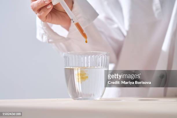 the girl drops medicine into the water. - iodine stock pictures, royalty-free photos & images