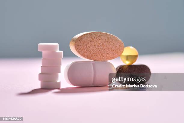 pills, vitamins and nutritional supplements on a pink background are stacked in bizarre figures. - streptomyces antibioticus imagens e fotografias de stock