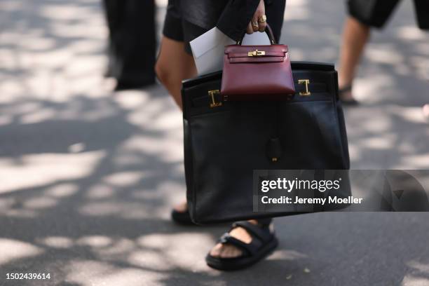 Fashion Week guest is seen wearing a black leather Hermes 50 Birkin bag and Bordeaux red Hermes mini Kelly bag outside the Hermes show during the...