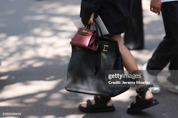 Fashion Week guest is seen wearing a black leather Hermes 50 Birkin bag and Bordeaux red Hermes mini Kelly bag outside the Hermes show during the...