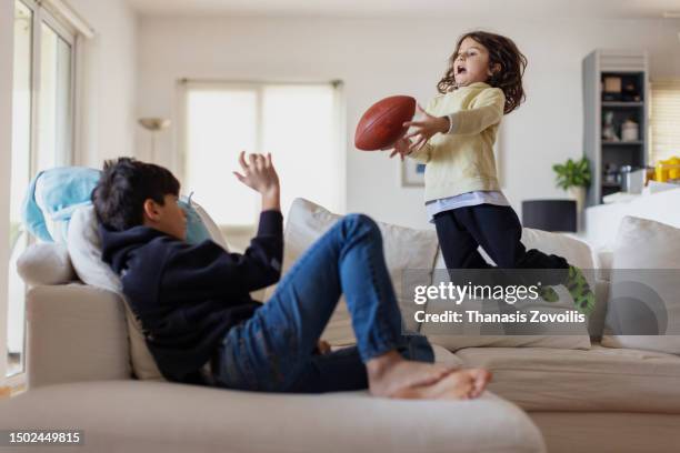 kids playing in the living room with a rugby ball - kids rugby stock pictures, royalty-free photos & images