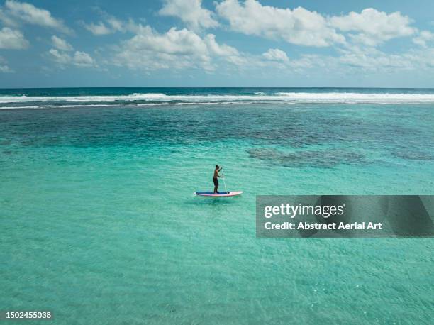 aerial shot showing one man paddle boarding on the indian ocean, uluwatu, bali, indonesia - bali stock pictures, royalty-free photos & images