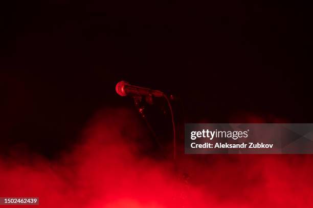 microphone on stage, against the background of bright stage smoke. karaoke, night club, bar. a musical concert. a scene with multicolored lights. song, musical concept. the spotlight shines brightly through the darkness. music and lighting equipment. - concert speakers stock pictures, royalty-free photos & images