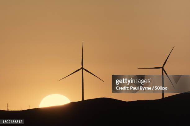silhouette of wind turbines on mountain against sky during sunset,midelt,morocco - midelt photos et images de collection