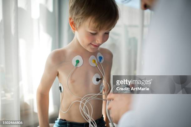 doctor adjusting  ecg holter monitor for a child to check his heart health - stress test stock pictures, royalty-free photos & images