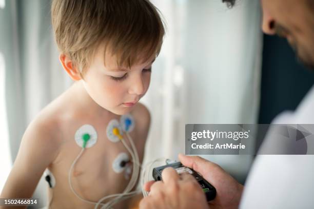 arzt stellt ekg-holter-monitor für ein kind ein, um seine herzgesundheit zu überprüfen - kardiologe stock-fotos und bilder