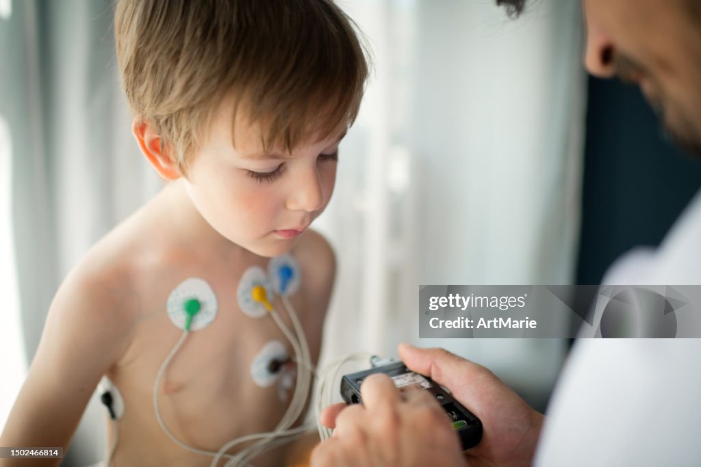 Médico ajustando o monitor de holter de ECG para uma criança para verificar sua saúde cardíaca