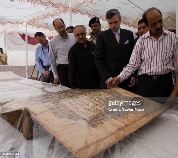 Chief minister of Jammu and Kashmir Omar Abdullah , flanked by other dignitaries, looks at an oversized centuries old Quranic manuscript at an...