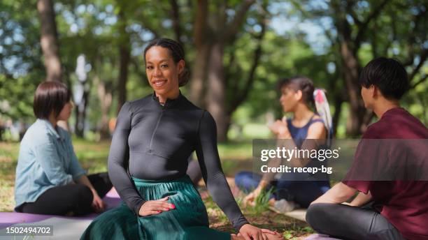 portrait of young woman looking at camera and smiling during group therapy session in nature - connected mindfulness work stock pictures, royalty-free photos & images