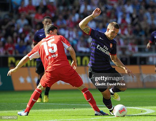 Lukas Podolski of Arsenal skips round Tobias Strobl of Cologne in action against FC Cologne during Pre-Season Friendly game at Rhein Energie Stadium...