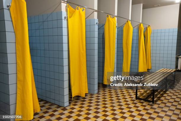 public shower room with shower cabins. a large, empty public shower room with bright walls. toilet and locker room of a swimming pool, sports club and fitness center, school, college, dorm or hostel. the concept of hygiene and healthy lifestyle. - hostel room stockfoto's en -beelden