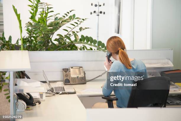 woman in reception talking on phone - busy hospital lobby stockfoto's en -beelden