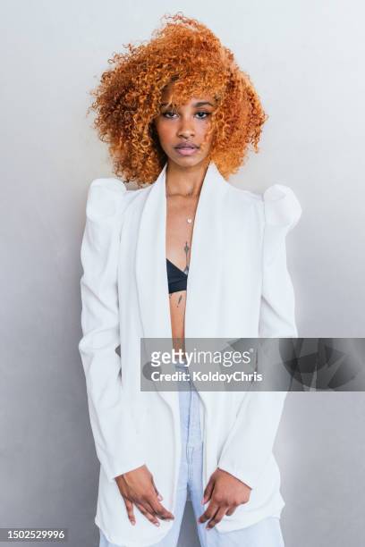 contrasting elegance: young latina model, afro-styled orange hair, white jacket, kicked wall - dyed hair stock pictures, royalty-free photos & images