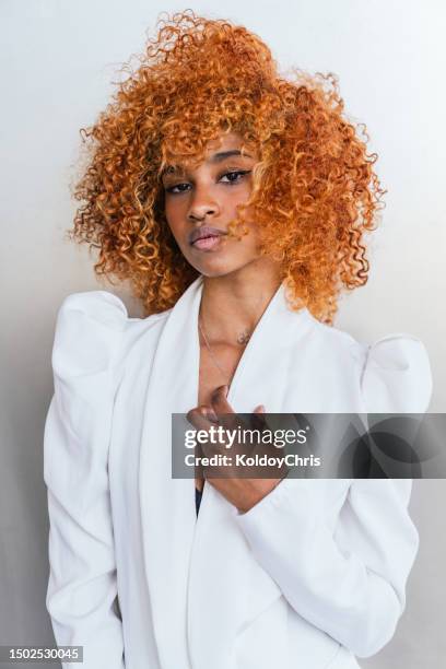 vibrant afro-latina model: elegant contrast of orange voluminous hair and white jacket against graffiti wall - big hair stock pictures, royalty-free photos & images